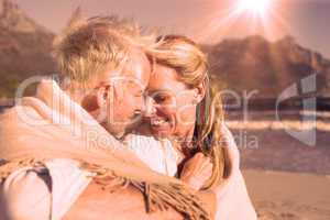 Smiling couple sitting on the beach under blanket