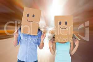 Composite image of couple wearing emoticon face boxes on their h