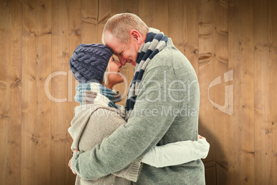 Composite image of happy mature couple in winter clothes hugging Composite image of happy mature couple in winter clothes hugging