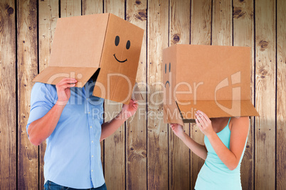 Composite image of couple wearing emoticon face boxes on their h