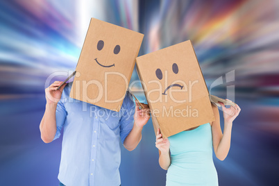 Composite image of couple wearing sad face boxes on their heads