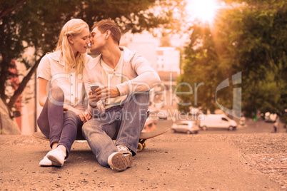 Cute young couple sitting on skateboard kissing