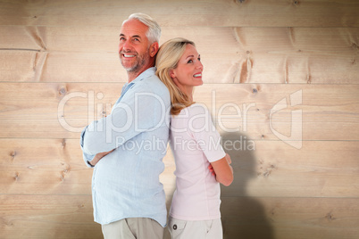 Composite image of smiling couple standing leaning backs togethe