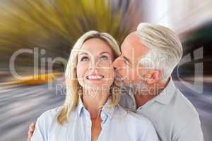 Composite image of affectionate man kissing his wife on the chee