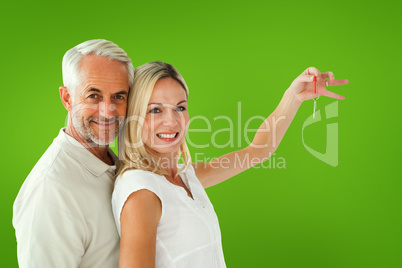 Composite image of happy couple showing their new house key Composite image of happy couple showing their new house key