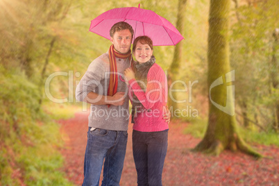 Composite image of couple standing underneath an umbrella