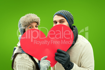 Composite image of attractive young couple in warm clothes holdi