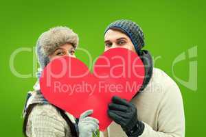 Composite image of attractive young couple in warm clothes holdi