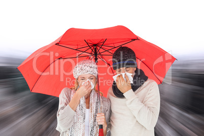 Composite image of couple in winter fashion sneezing under umbre