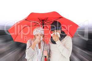 Composite image of couple in winter fashion sneezing under umbre