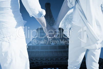 Composite image of couple on the beach looking out to sea holdin