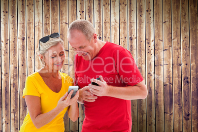 Composite image of happy mature couple looking at smartphone tog