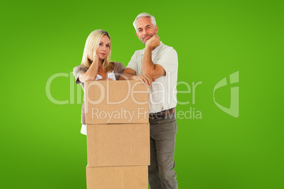 Composite image of happy couple leaning on pile of moving boxes