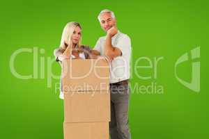 Composite image of happy couple leaning on pile of moving boxes