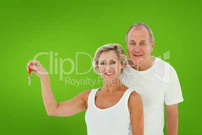 Composite image of mature couple smiling at camera with new hous