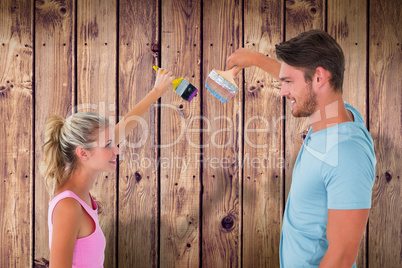 Composite image of young couple painting with brushes