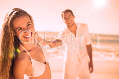 Pretty woman smiling at camera with boyfriend holding her hand