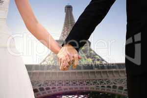 Composite image of mid section of newlywed couple holding hands