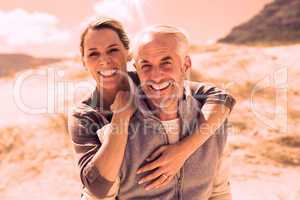 Happy hugging couple on the beach looking at camera