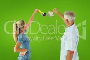 Composite image of happy couple painting wall with paintbrushes