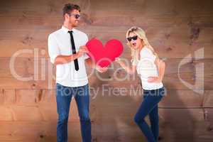 Composite image of cool young couple holding red heart