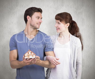 Composite image of couple holding a model house