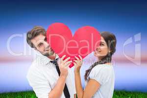 Composite image of couple smiling at camera holding a heart