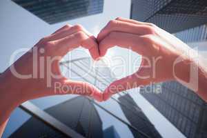 Composite image of hands making heart shape on the beach