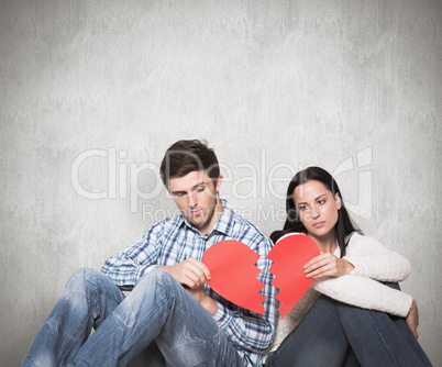 Composite image of young couple sitting on floor with broken hea