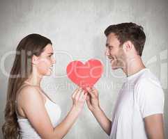 Composite image of romantic young couple holding heart