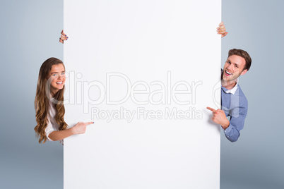 Composite image of happy young couple with blank board