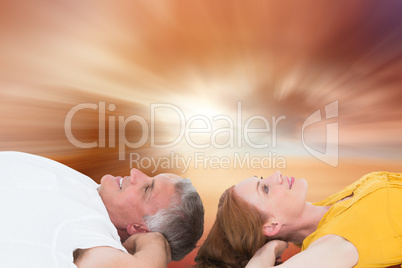 Composite image of casual couple lying on floor