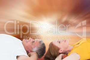 Composite image of casual couple lying on floor