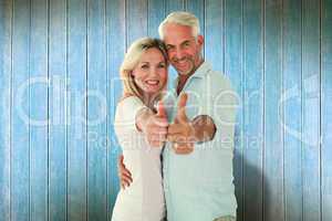 Composite image of smiling couple showing thumbs up together