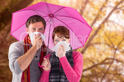 Composite image of couple standing underneath an umbrella