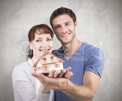 Composite image of couple holding a model house