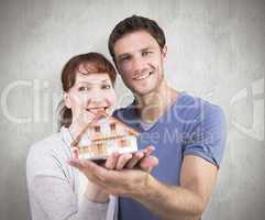 Composite image of couple holding a model house