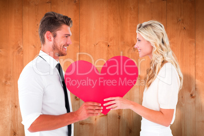 Composite image of attractive young couple holding red heart