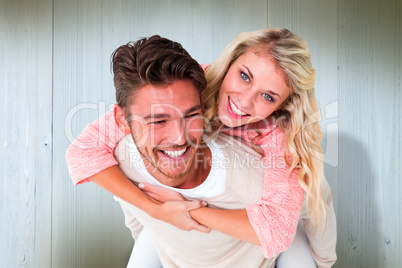 Composite image of handsome man giving piggy back to his girlfri