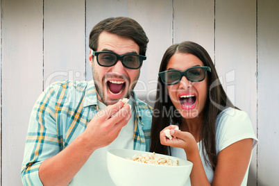 Composite image of attractive young couple watching a 3d movie