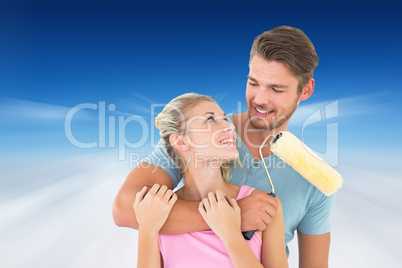 Composite image of young couple hugging and holding paint roller