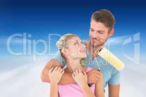 Composite image of young couple hugging and holding paint roller