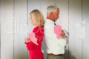 Composite image of couple holding two halves of broken heart