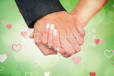 Composite image of newlyweds holding hands close up