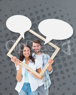 Composite image of happy young couple holding picture frame