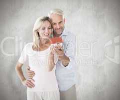 Composite image of happy couple holding miniature model house