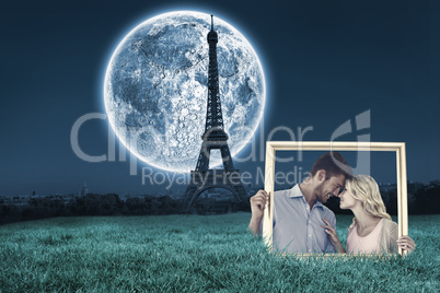 Composite image of attractive young couple holding picture frame