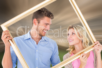 Composite image of attractive young couple holding picture frame