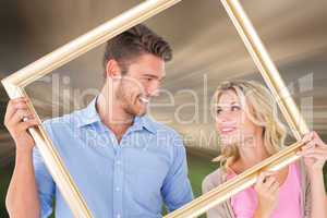 Composite image of attractive young couple holding picture frame