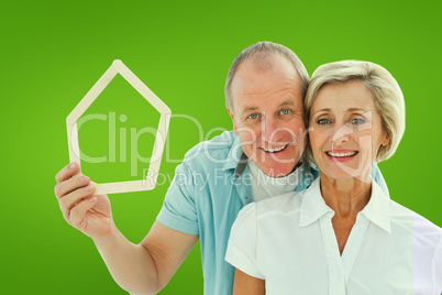 Composite image of happy older couple holding house shape